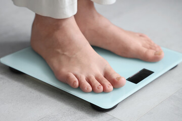 Young woman standing on scales at home, closeup. Weight loss concept