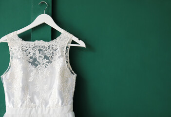 Wedding dress hanging on green wall, closeup