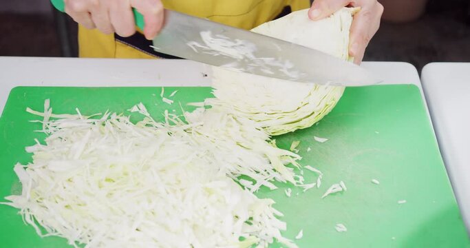 Cook cuts the cabbage into thin slices to make a salad.