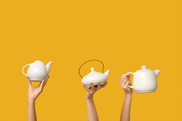 Women with ceramic teapots on yellow background