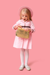 Cute little girl with stylish golden purse on pink background