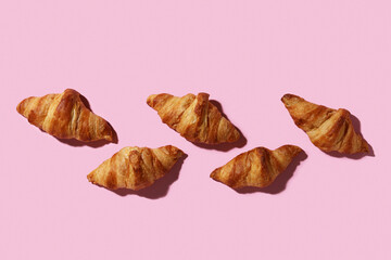Many tasty croissants on pink background