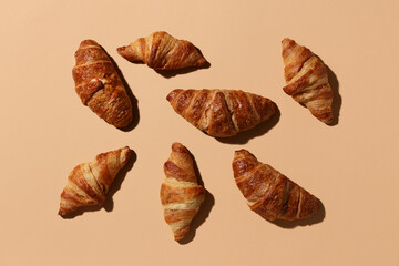 Many tasty croissants on brown background