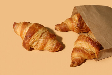 Paper bag with tasty croissants on brown background