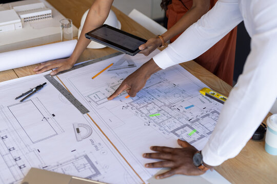Diverse team working on architectural plans in office, focusing on blueprints