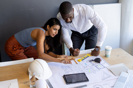 Diverse team working on architectural plans in office, focusing on blueprints - Powered by Adobe