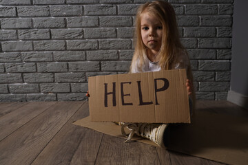 Homeless little girl begging for help near grey brick wall