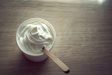 A bowl of Greek yogurt on a wooden table in a top view