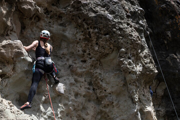 Obraz premium Sporty woman climbing on rock wall