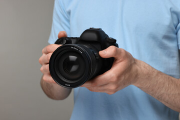 Photographer holding camera on grey background, closeup
