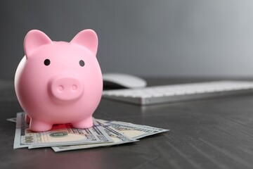 Pink piggy bank and banknotes on black table, space for text