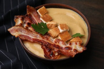 Delicious lentil soup with bacon and parsley in bowl on table, closeup
