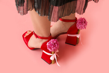 Legs of beautiful young woman in ankle straps heels with hyacinth flowers on pink background
