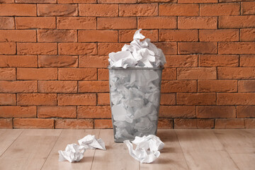 Recycling bin with paper near brown brick wall. Recycle concept