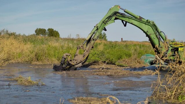Modern dredger equipment removes debris from pond dredging bottom. Professional heavy equipment for effective cleaning of polluted water