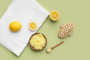 Composition with natural body scrub, massage brush, towel and lemons on green background