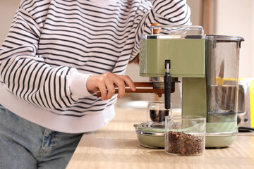 Beautiful young woman with modern coffee machine in kitchen, closeup