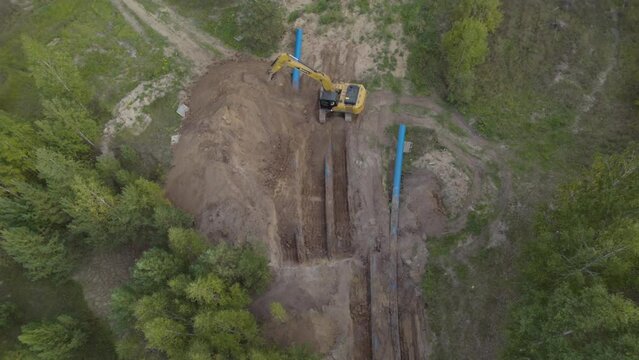 Modern excavator digs trench for installing new pipelines. Bucket releases ground on pile preparing surface for pipes replacement task