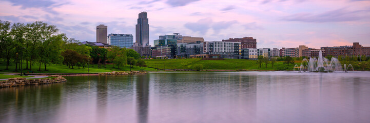 Omaha City Skyline, high-rising buildings, peaceful lake, big sky with floating clouds: The beauty of the midwestern metropolis in Nebraska