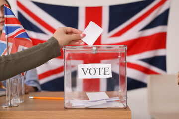 Voting young woman near ballot box with UK flag at polling station, closeup