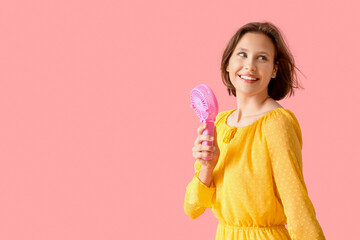 Young woman with small electric fan on pink background