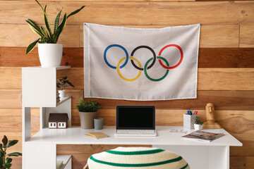 Modern workplace and Olympic flag on wooden wall in office