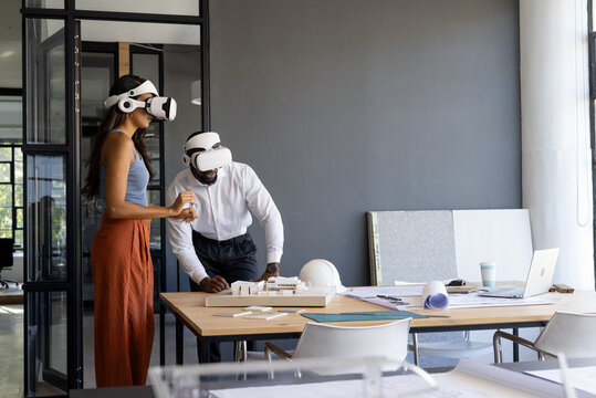 Colleagues in office using virtual reality headsets while working on project, copy space