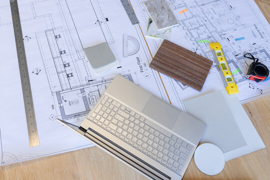 Architectural drawings and materials are spread out on wooden table