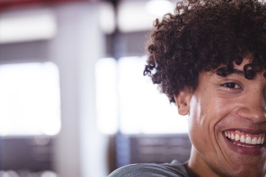Young biracial man fitness enthusiast smiling at gym, copy space