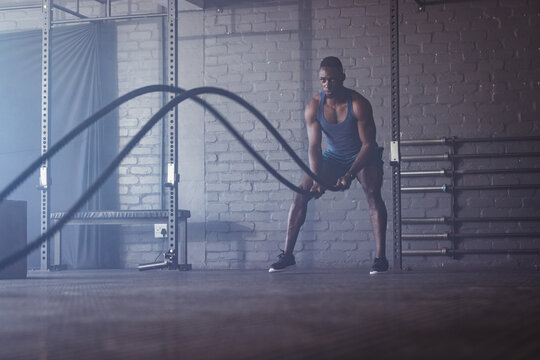 Strong and fit African American man training with battle ropes at gym - Powered by Adobe