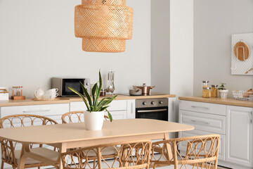 Interior of modern kitchen with white counters, dining table, chairs and lamp