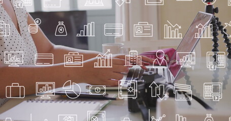Image of multiple icons over midsection of caucasian woman using laptop