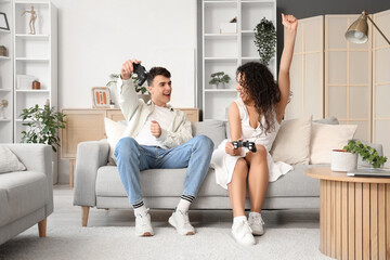 Young couple in love playing video game on sofa at home
