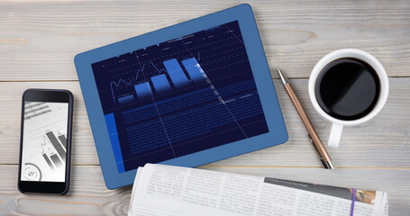 Devices on table displaying financial charts, alongside a coffee cup