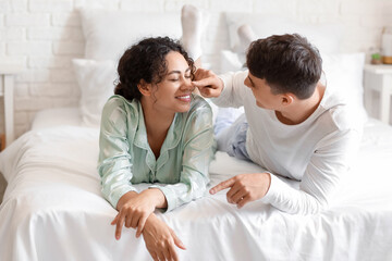 Fototapeta premium Young man touching his girlfriend's nose in bedroom