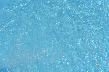 Blue water with ripples on the surface. Defocus blurred transparent blue colored clear calm water surface texture with splashes and bubbles. Water waves with shining pattern texture background.