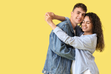 Young couple in love hugging on yellow background