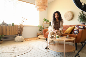 Young African-American witch with crystal ball recording video at home