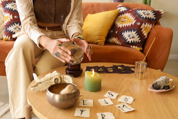 Young witch with crystal ball on table at home, closeup