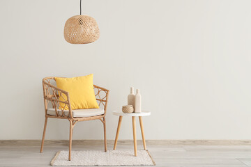 Wicker armchair with yellow pillow and table near light wall in room