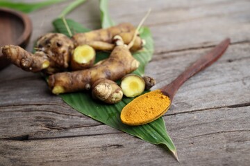 Turmeric root powder on wood background