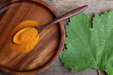 Turmeric root powder on wood background