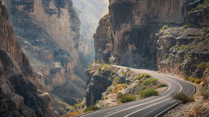 A dramatic mountain road with steep inclines and sharp turns, surrounded by towering cliffs and...