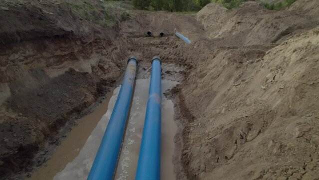 Long durable water pipelines installed in ditch with puddle. Municipal water supply system in state of installation for quality services