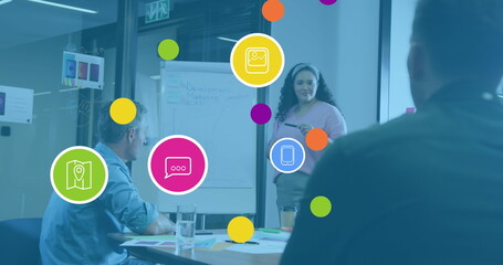 Image of social media icons over diverse business people having meeting at office