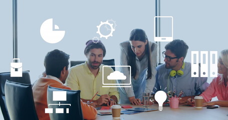 Image of multiple digital icons against diverse colleagues discussing together at office