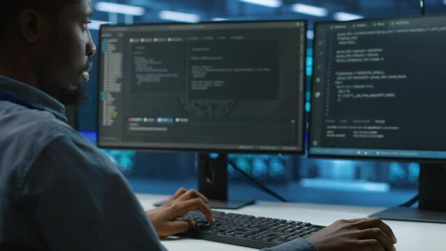 Technician doing system analysis, typing data on PC, doing needed adjustments in supercomputers server farm housing advanced data storage infrastructure supporting critical IT workloads, close up