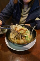 asian women use chopsticks to tong noodle on grilled pork ramen noodle