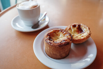 Close-up of two Portuguese custard tarts, also known as Pastéis de Nata, served on a white plate.