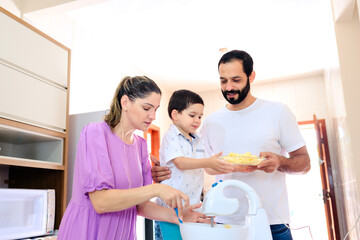 Brazilian family baking together at home, using a mixer to make a cake. The family consists of mom, dad, and young son, and the image captures love and togetherness in a joyful family moment.